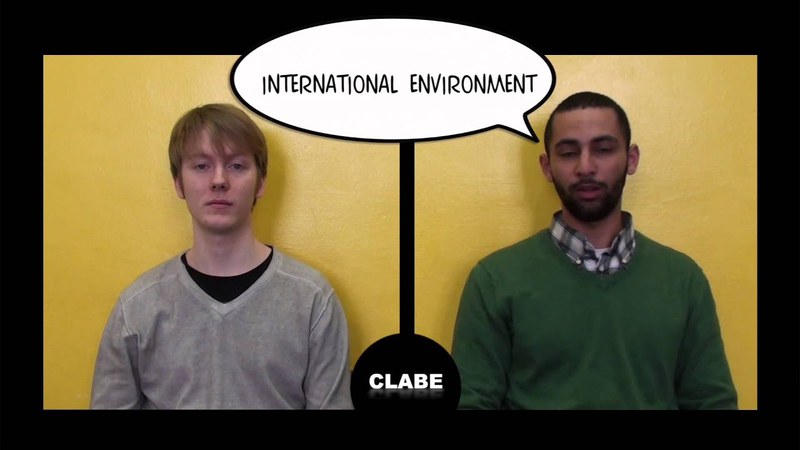 The frame is split into two halves. In each of them there is a man. On the left there's a white blond man with a grey cardigan. On the left, a brown man with a green cardigan over a checkered shirt, a bubble message spellling "INTERNATIONAL".