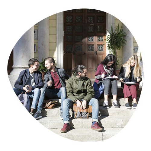 Group of students sitting on university entrance steps
