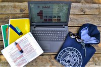 immagine con un portatile, felpa con logo UniBo, quaderni e pennarelli