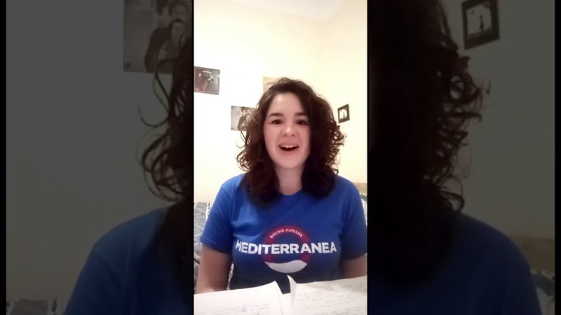 Una ragazza dai capelli mori ricci con una maglietta a maniche corte blu di Mediterranea.