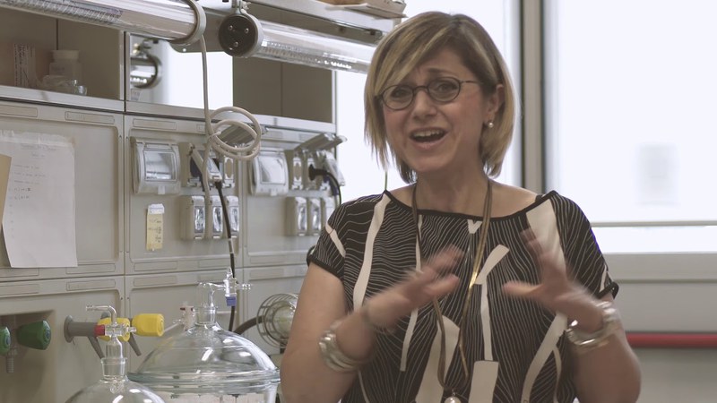 Una donna con capelli corti e biondi e occhiali è all'interno di un laboratorio e parla davanti alla telecamera.