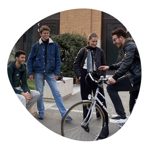 Gruppo di studenti di cui uno in bicicletta che ridono insieme in ambiente esterno