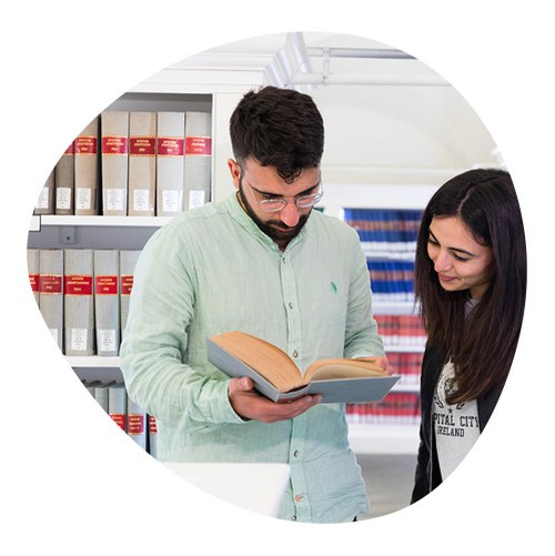 Studenti, un ragazzo e una ragazza, che consultano un libro in biblioteca